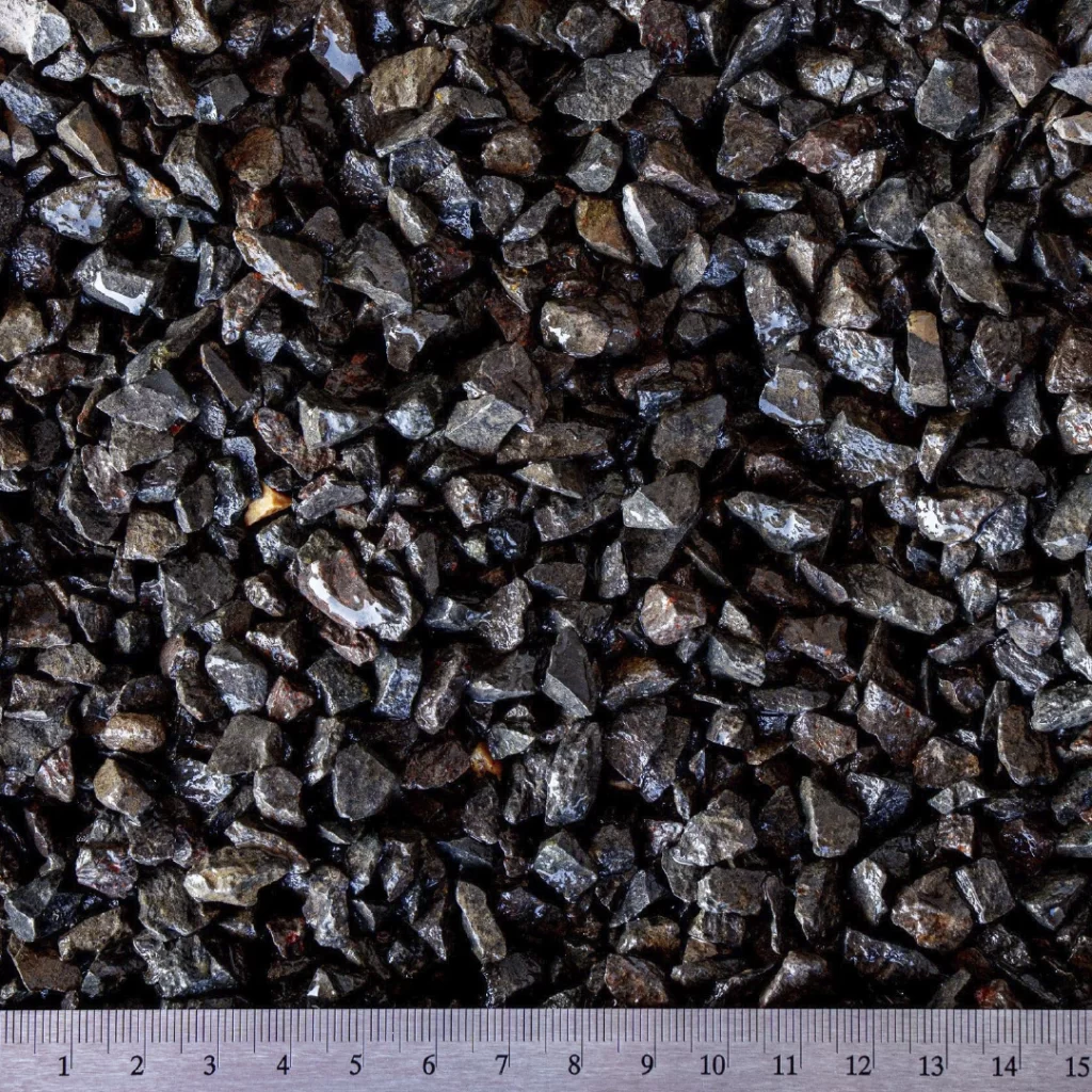 Detailní pohled na lomový kámen o velikosti 4–8 mm, směs drcených kamenných fragmentů tmavší barvy, s občasnými lesklými povrchy.