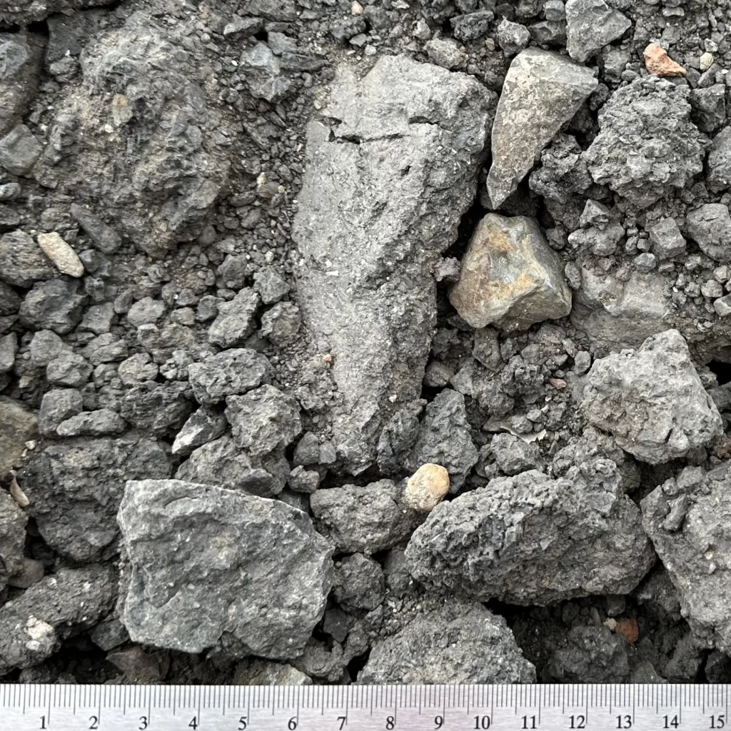 Směs netříděného živičného recyklátu s částicemi o velikosti 0–125 mm, složená z různě velkých kusů drceného asfaltu a menších fragmentů, používaných v stavebnictví nebo údržbě silnic.