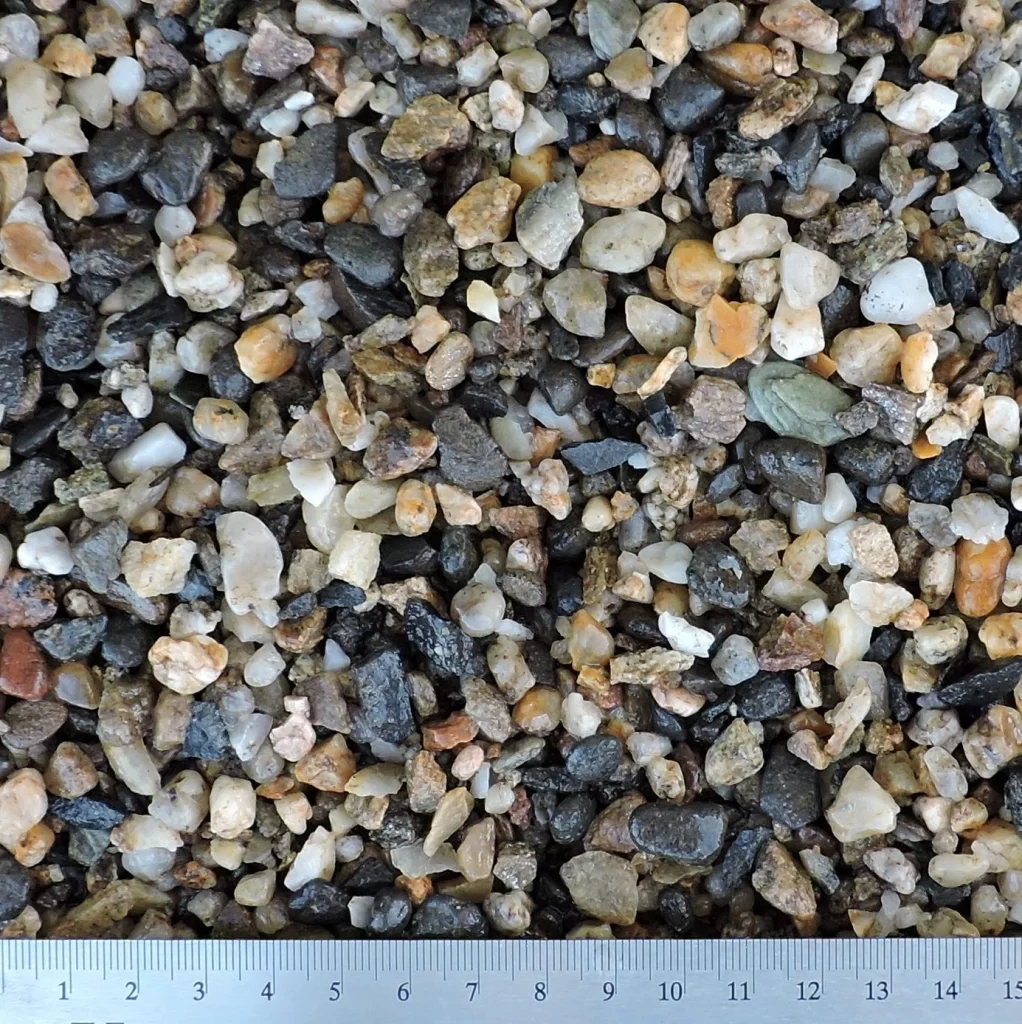Detailní záběr na drcené kamenivo o velikosti 4–8 mm. Materiál obsahuje různě barevné kamínky různých tvarů a textur.