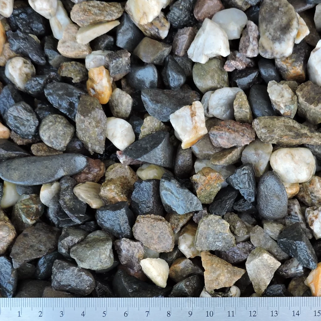 Detailní záběr na drcené kamenivo o velikosti 8–16 mm. Materiál obsahuje různě barevné kamínky různých tvarů a textur.